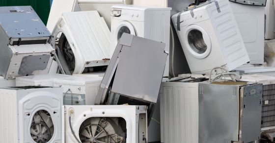 Pile de machines à laver usagées empilées à l’extérieur.